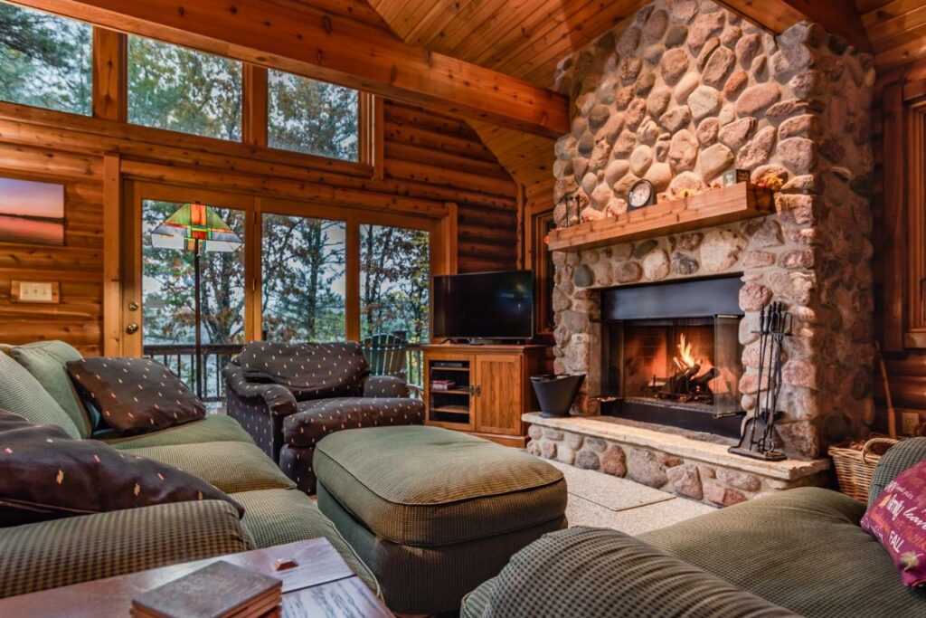 The living area of a log cabin with plush couches and a stone fireplace.