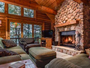 Living room of a ski resort in WI with large stone fireplace and gray furniture.