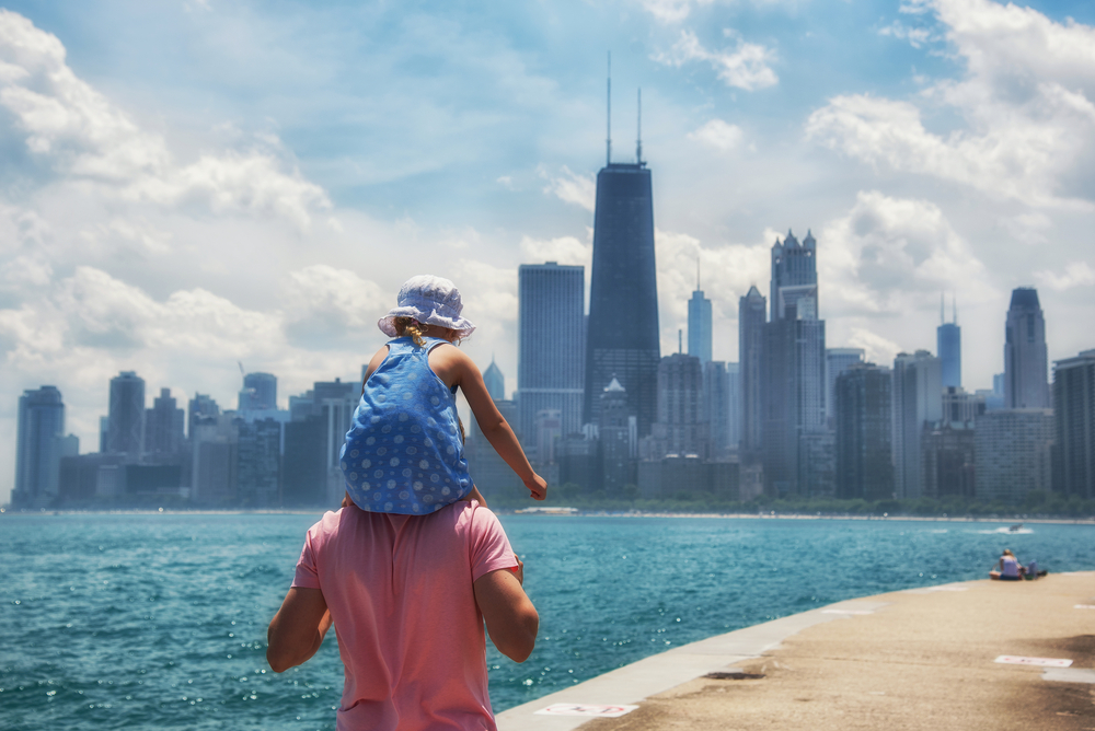 A person holding a child on their shoulders with the Chicago skyline in the background one of the best things to do in Chicago with kids