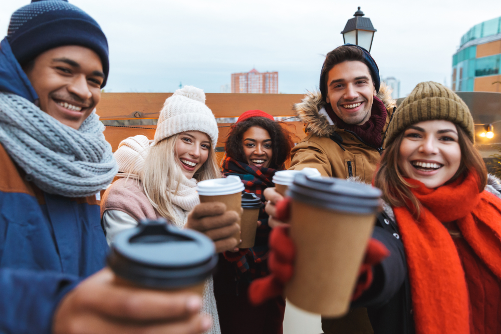 A group of young people holding up coffee cups to the camera