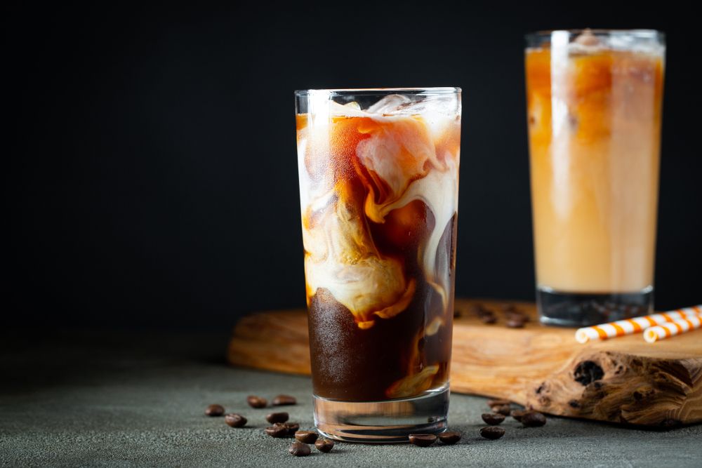 Two glasses of iced coffee with cream in them