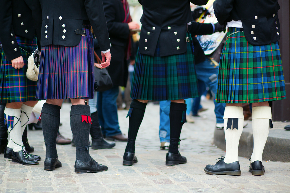 A view from the waist down of a group of people wearing kilts and traditional Celtic clothing