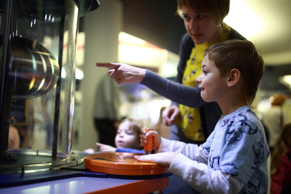 Children and an adult looking at an interactive exhibit at a science museum