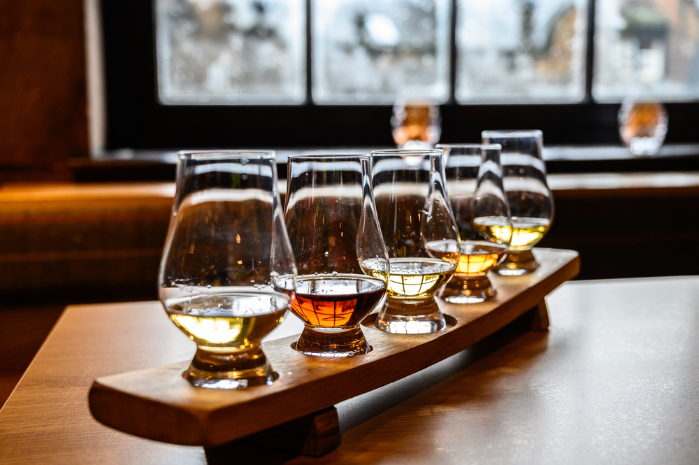 A flight of different colored whiskies and spirits in clear glasses
