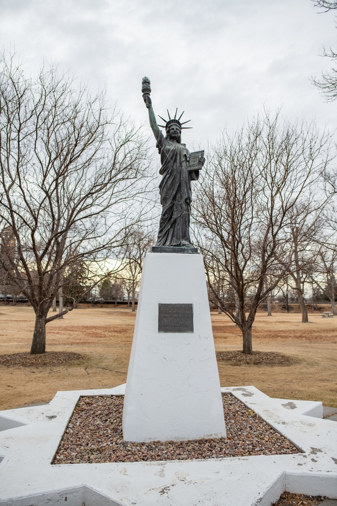 Miniature replica of the statue of liberty with bare trees behind it.