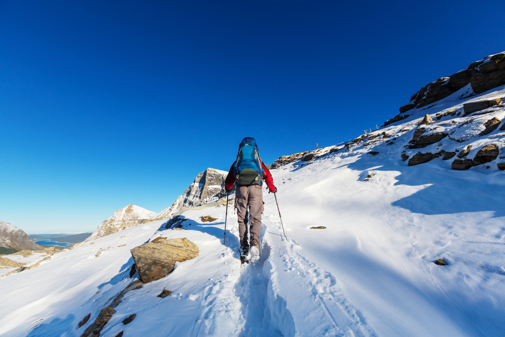 guy hiking on a snow mountain with backpack