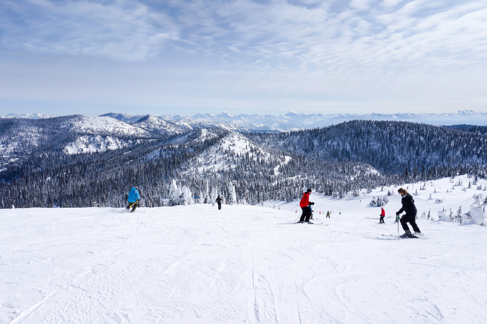 skiers skiing from the summit of a snow mountain