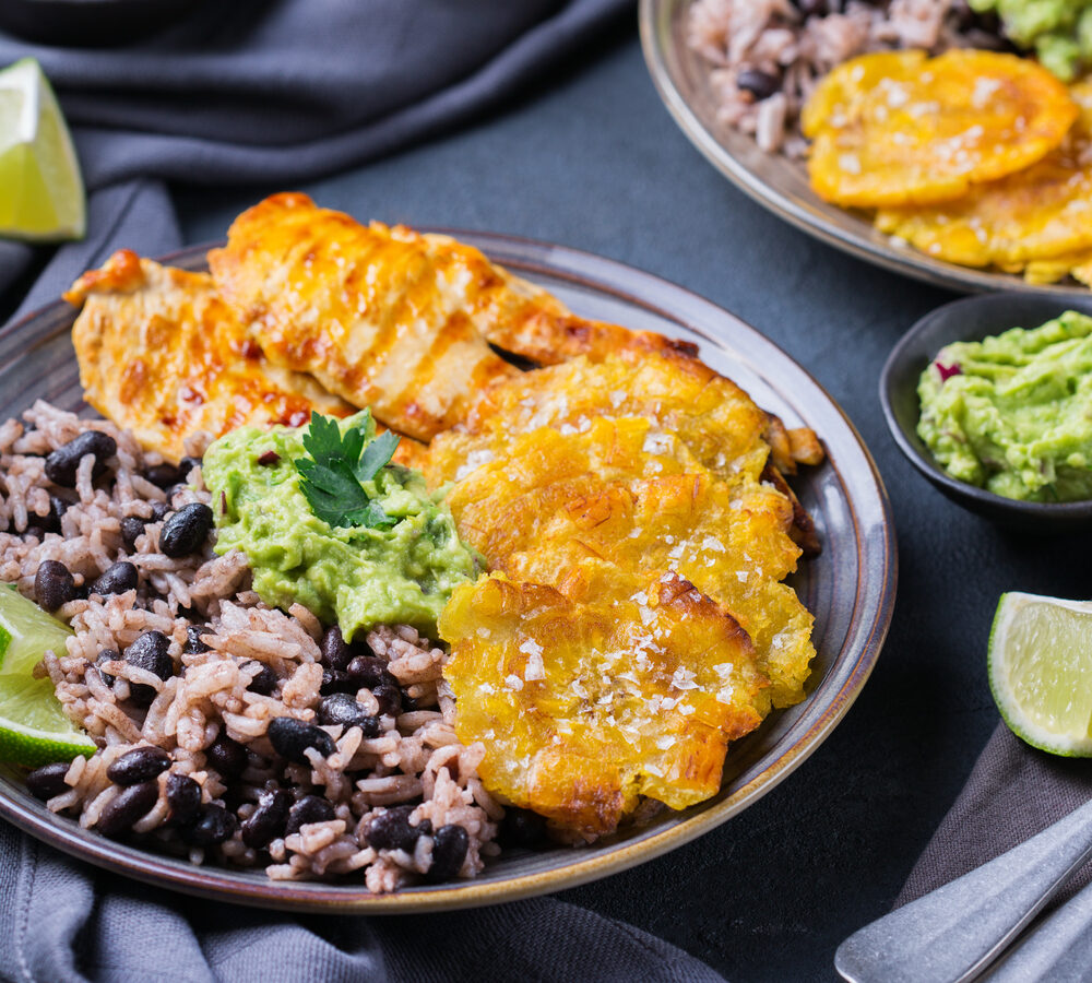 A plate of classic Cajun food with black beans and rice, grilled fish, and fried plantains. Similar to what you'll find at restaurants in Tulsa
