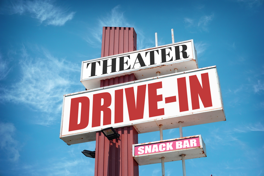 A sign for the entrance of a vintage Drive-In movie theater on a sunny day