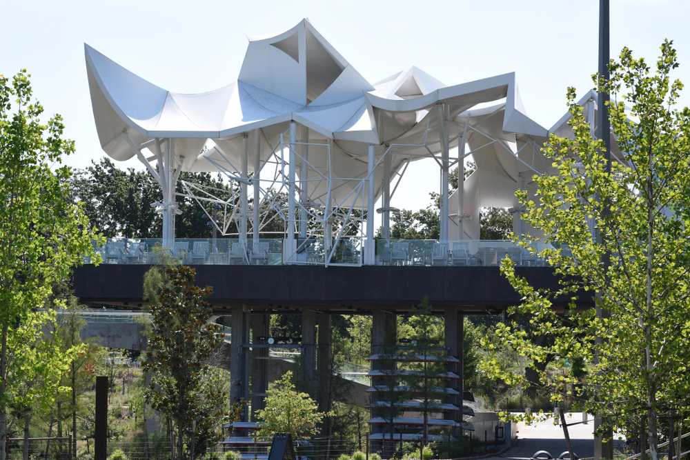 A large pavilion that is on a platform and features very angular architecture surrounded by trees