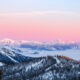 orange colored sky over snow covered forest and mountains winter in montana