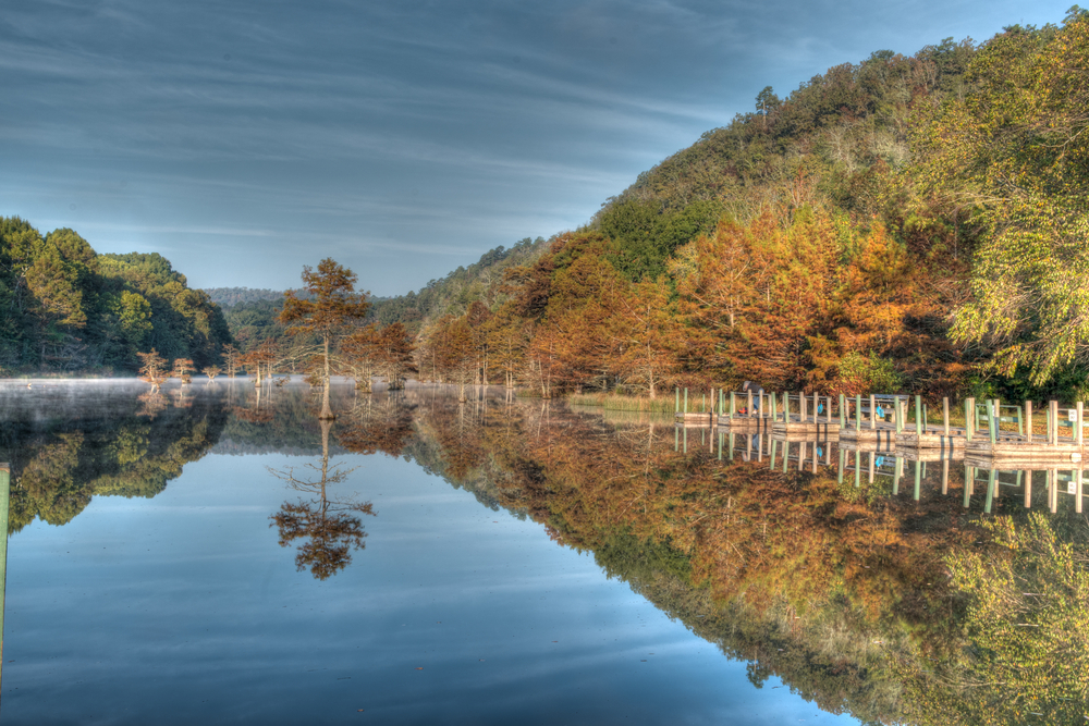 Broken Bow Lake reflecting the fall trees and boat docks on an overcast day.