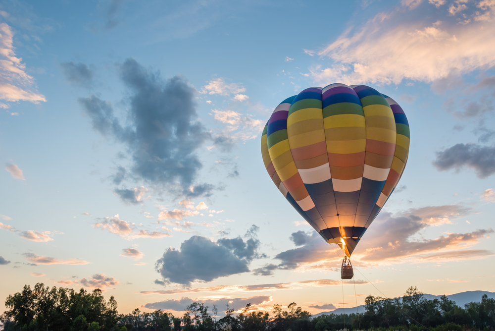 A colorful hot air balloon rising into the sunset.