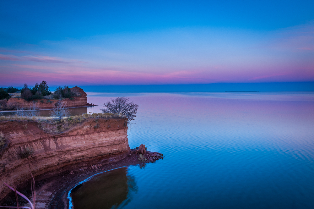 Pink coloured sky over a lake with sandstone bluff lakes in oklahoma