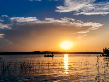 Setting sun over a lake as the boat rows lakes in Oklahoma