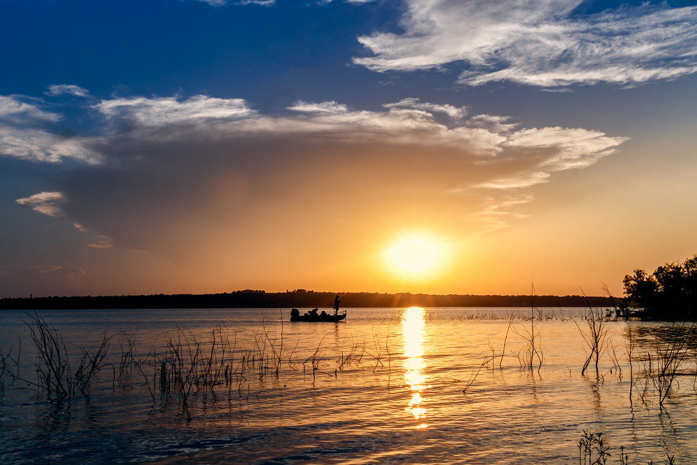 Setting sun over a lake as the boat rows lakes in Oklahoma