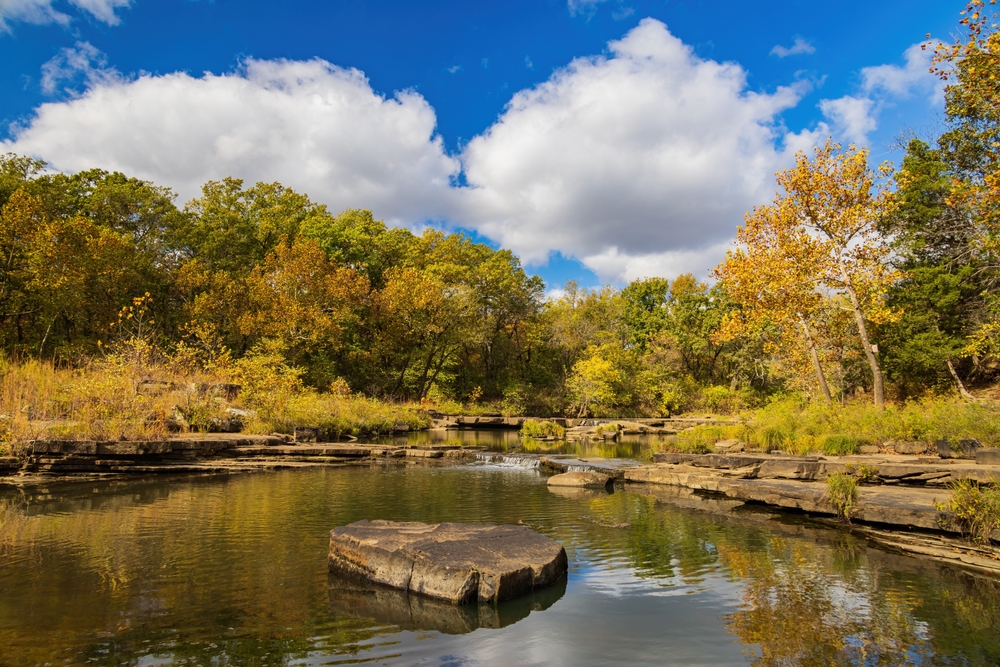 Lake with rocks along the edge and fall trees at Osage Hills State Park in Oklahoma.