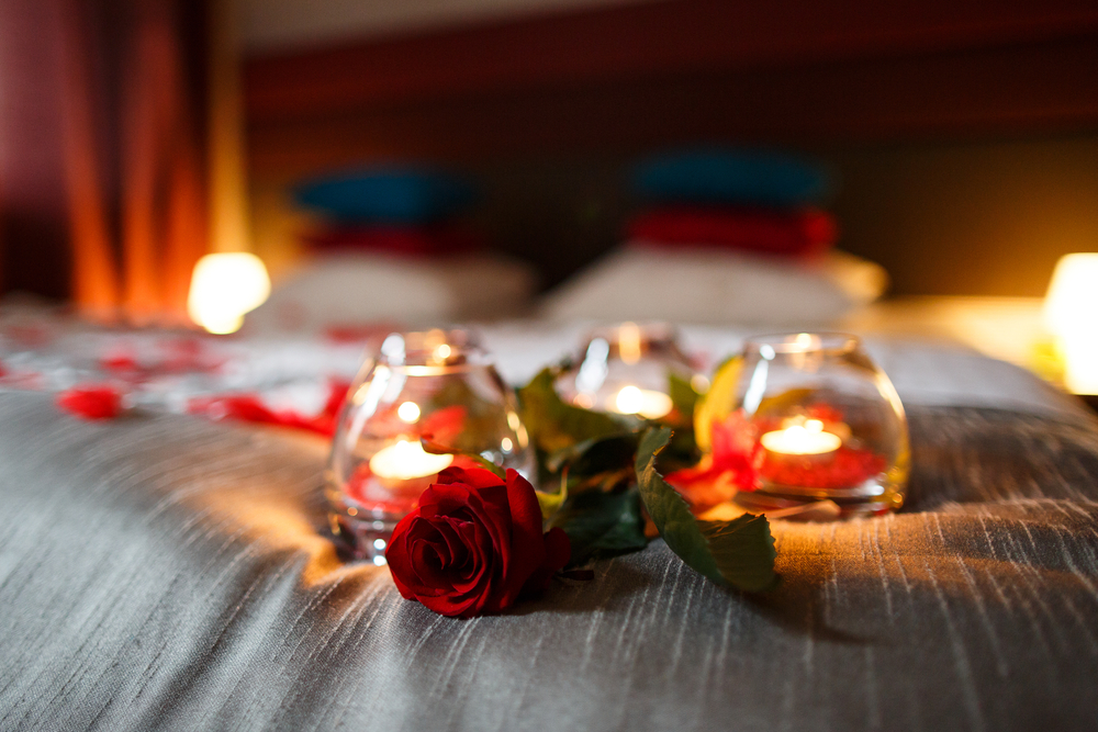 Romantic night. Rose and candles on bed. The article is about romantic getaways in Ohio.