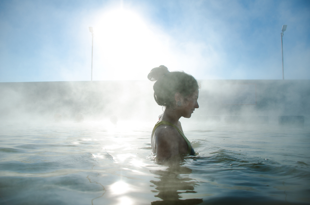 Woman with her hair ties up soaking in a steaming pool.