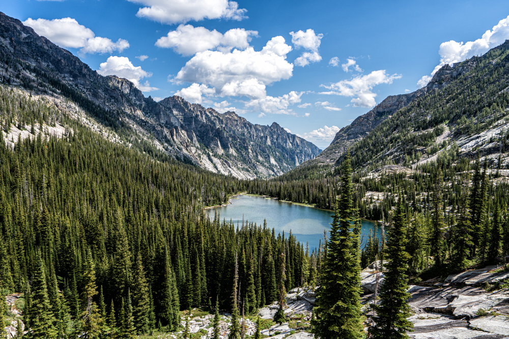mountains surrounding a blue lake and pine trees