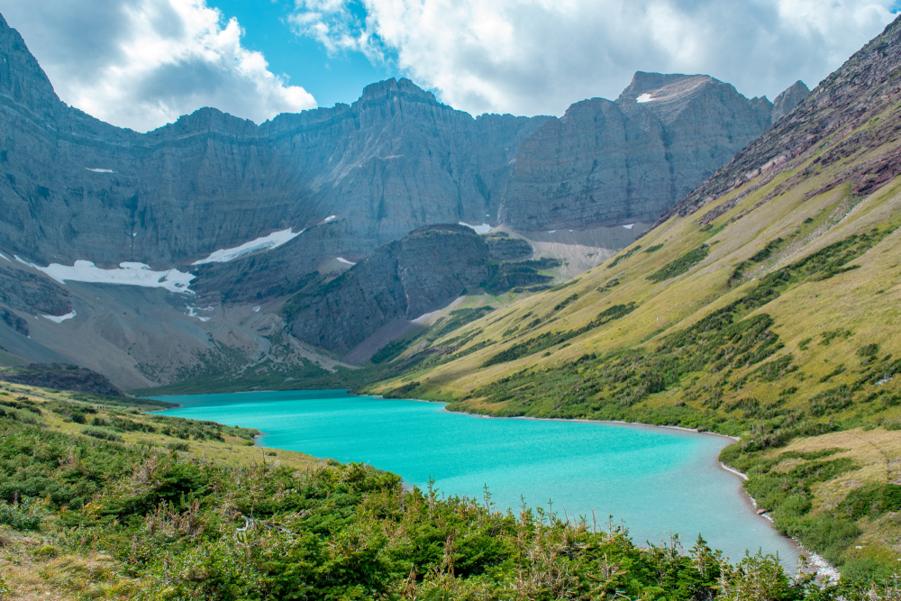 turquoise blue colored lake surrounded by mountains hiking in montana