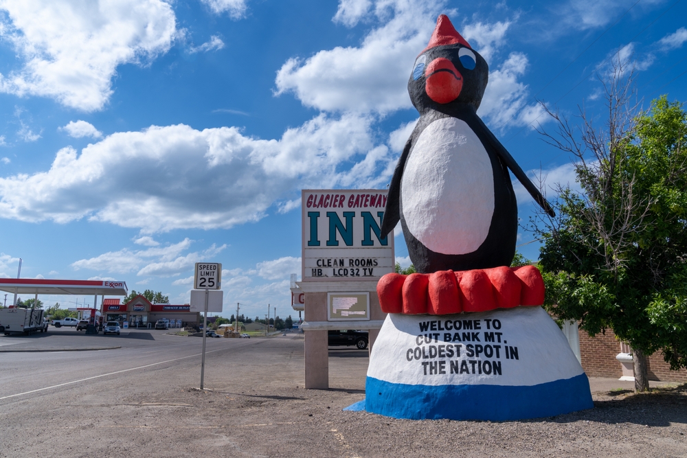 Tall, cartoonish penguin statue on the side of the road.