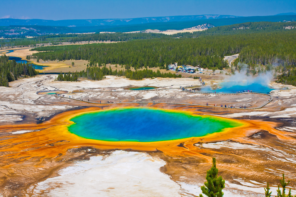 rainbow-colored hot spring surrounded by trees things to do in west yellowstone