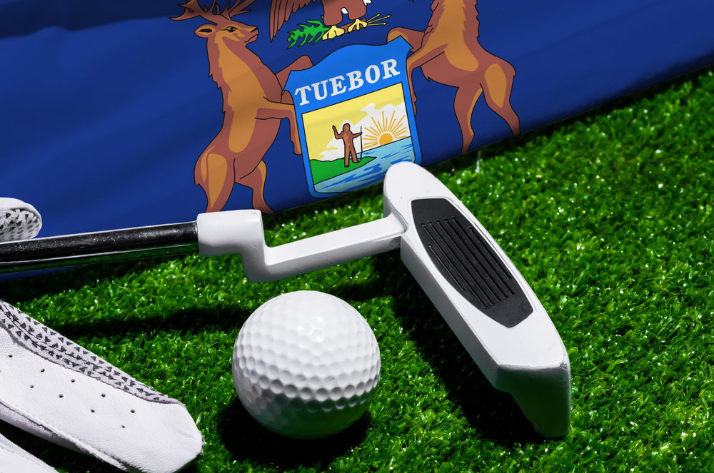 Golf ball and club with flag of Michigan on green grass