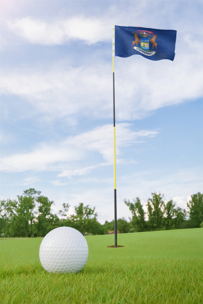 Michigan flag on golf course putting green with a ball near the hole
