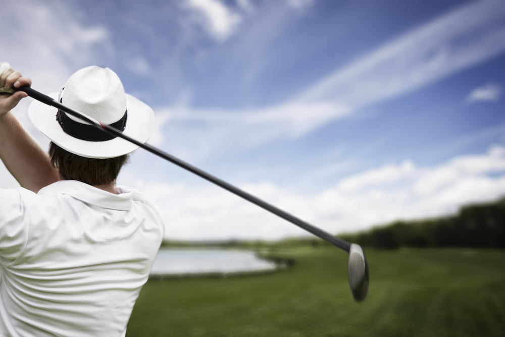 Close-up of male golf player with hat teeing-off at one of the best golf courses in Michigan.