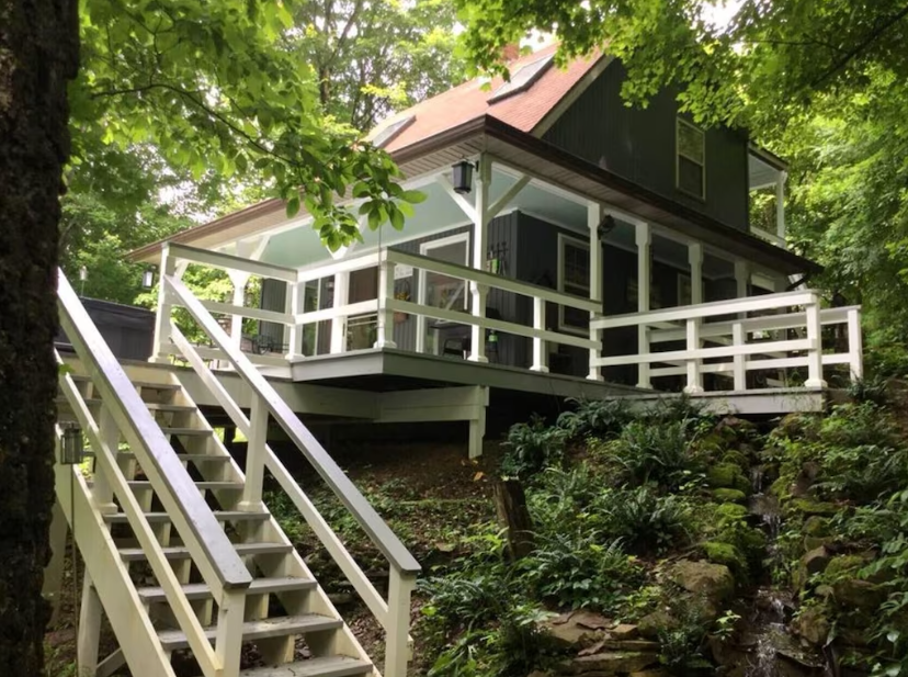 Picture shows a cabin up some steps among the trees. The article is about cabins with hot tubs. 