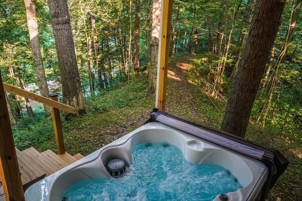 The picture shows a hot tub on a balcony. It is elevated and looks out over trees The article is about cabins with hot tubs.  