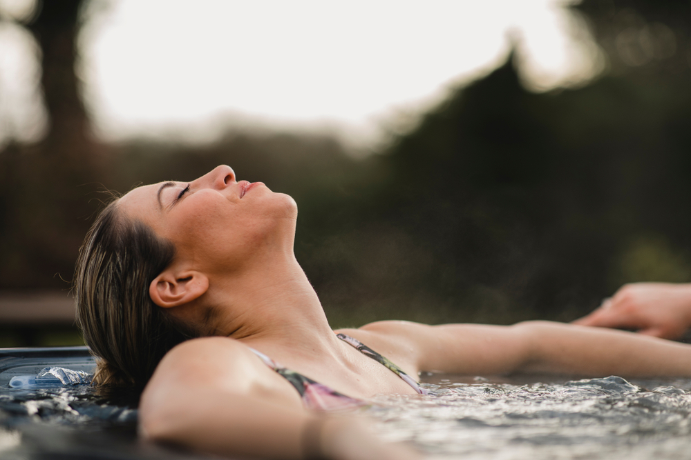 Close up of women in hot tub with her head laid back. The article is about cabins with hot tubs.  