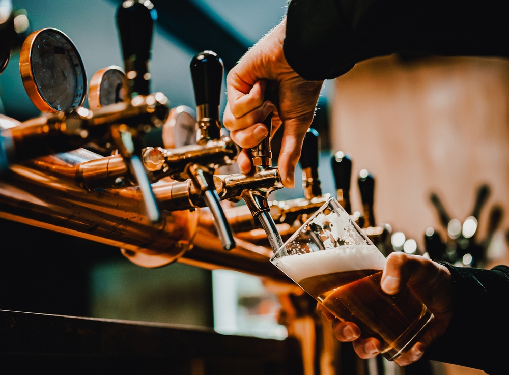 A person pouring a glass of beer from a tap.