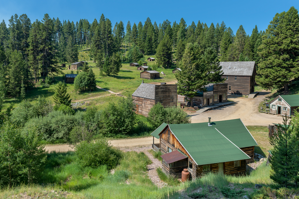 Looking down at the preserved buildings of Garnet Ghost Town surrounded by trees.