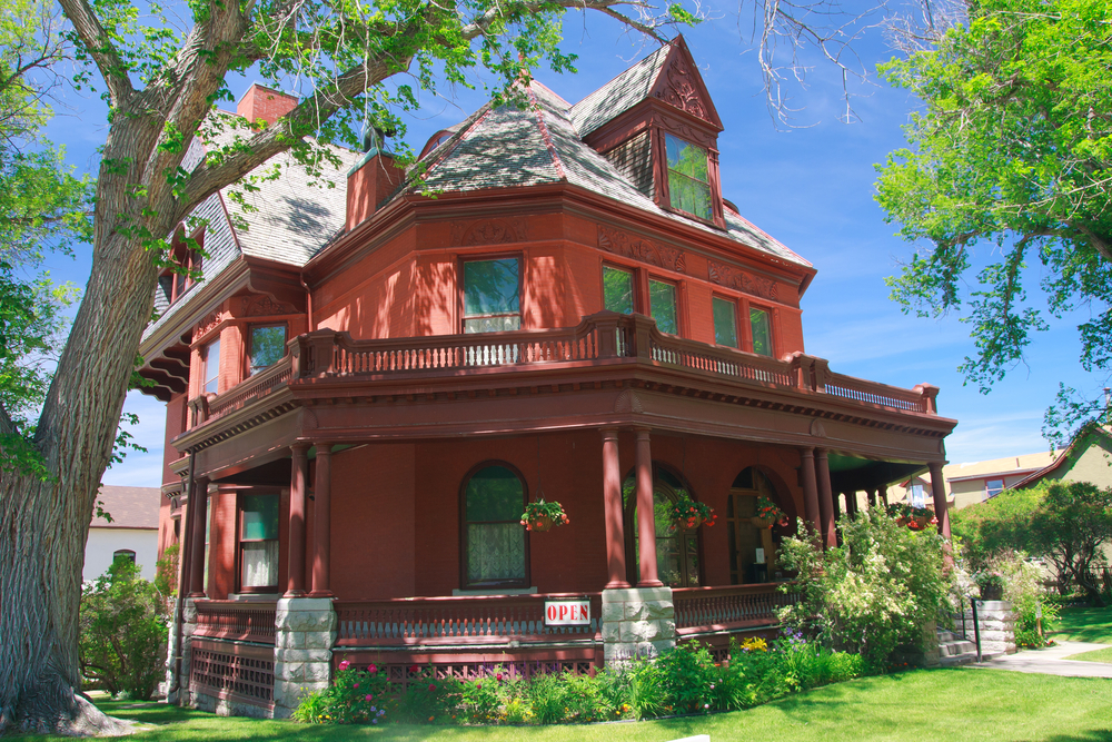 The red, Queen Anne style Original Governor’s Mansion with a flower garden around it.