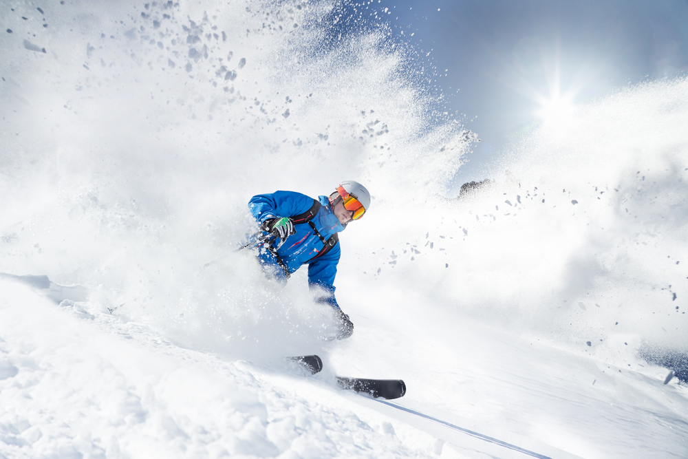 A skier going down a slope with powder flying everywhere.