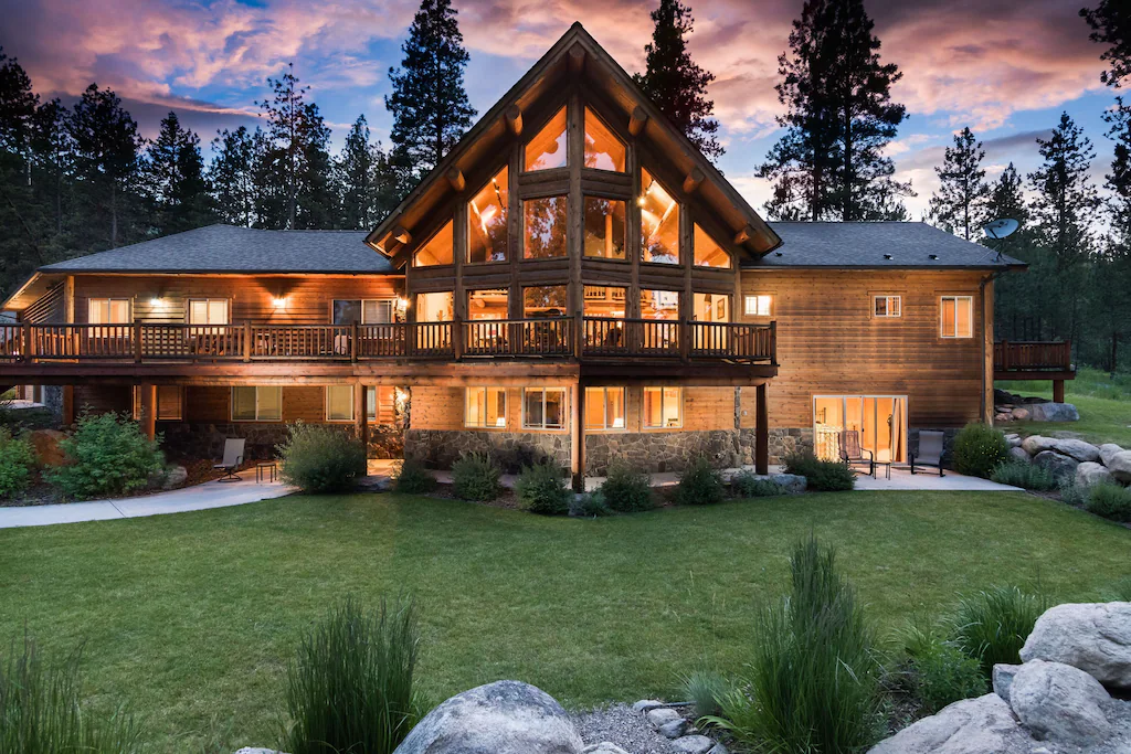 log home lit from inside surrounded by trees in the evening cabins in montana
