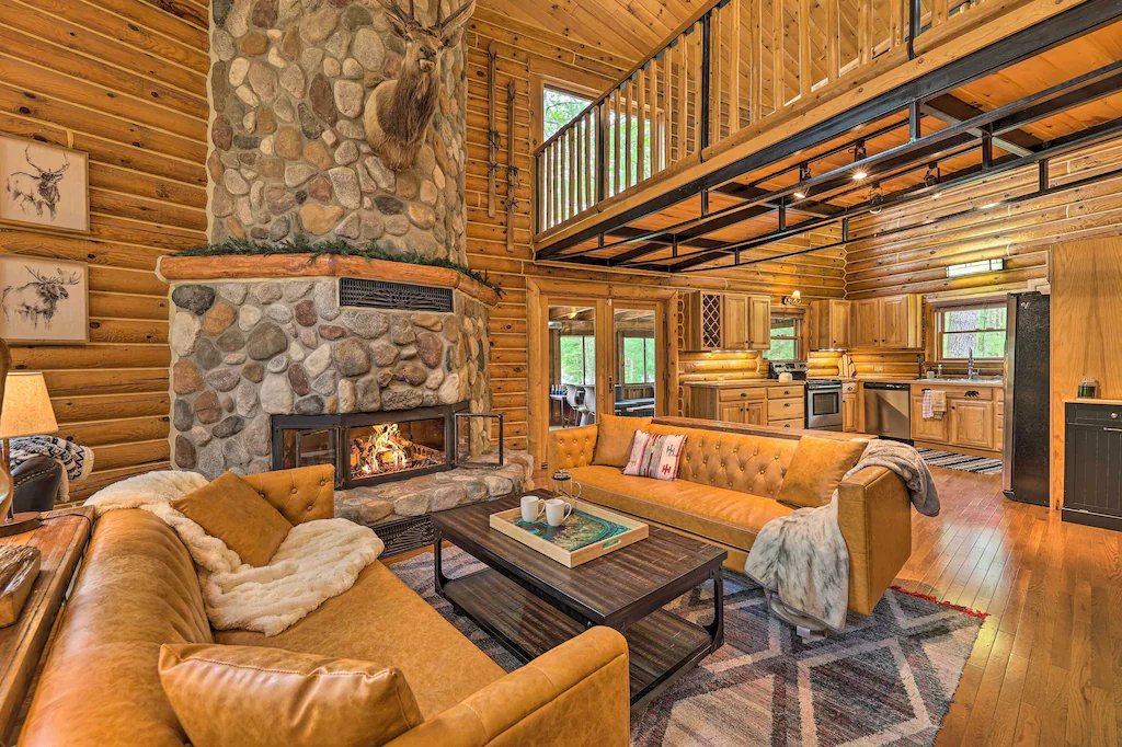 Large living area in a luxury cabin in Michigan. The picture shows two large sofas and a stone fireplace. 