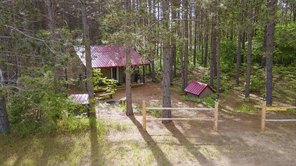small cabin in the woods. The cabins have red roofs and there is one small one and one large one.  