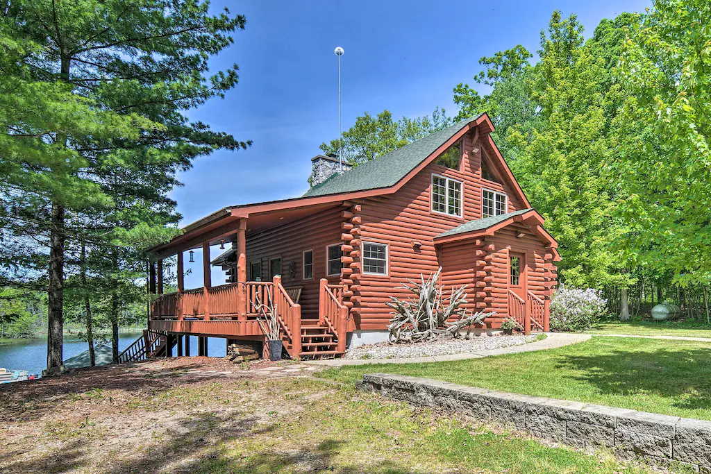 A log cabin in the woods with a lake in the background. The article is about cabins in Michigan