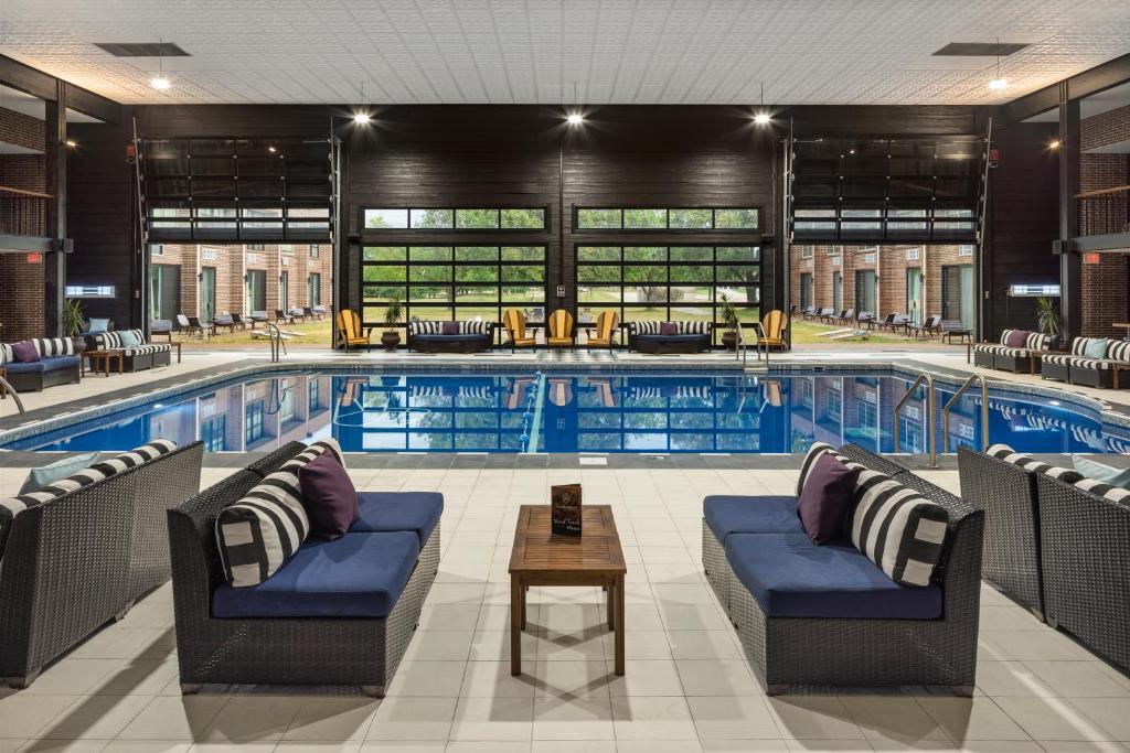 An indoor pool surrounded by black and yellow chairs. It is modern and stylisk with large open windows in the background. 