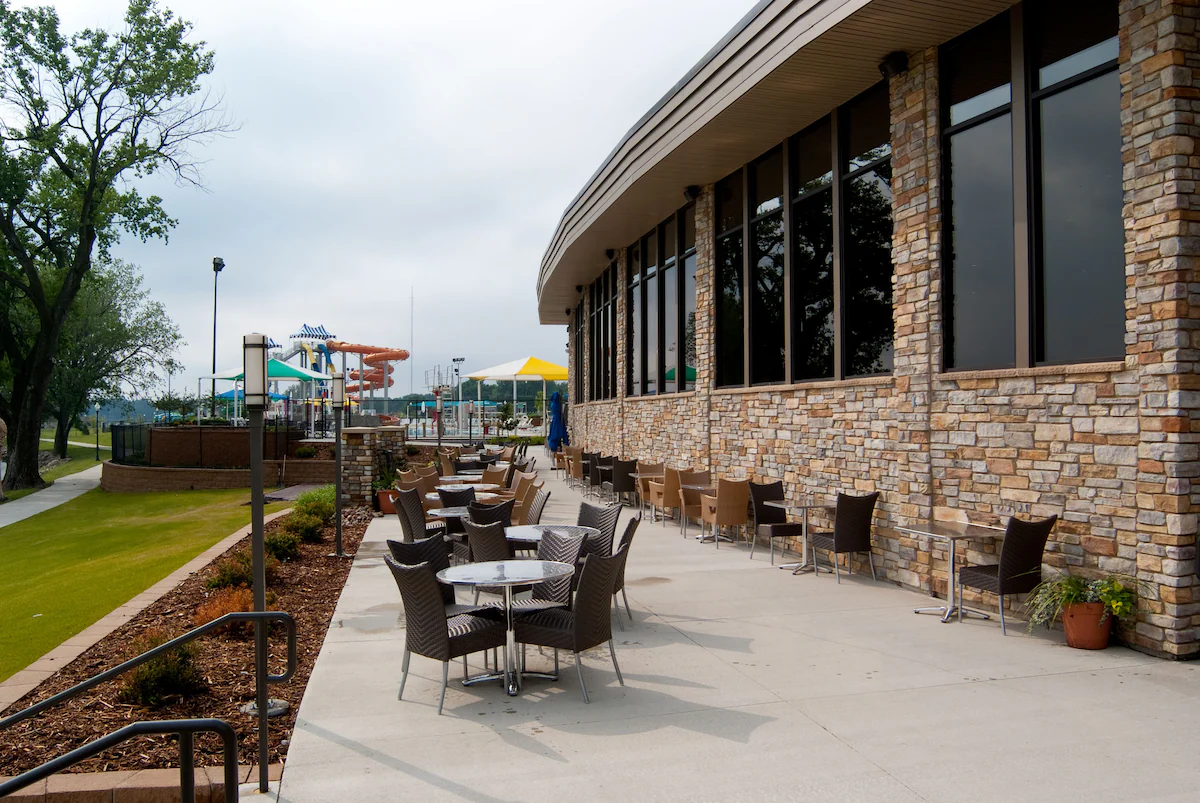 Outside seating area with a waterpark in the distance. There is a brick building to the side. 