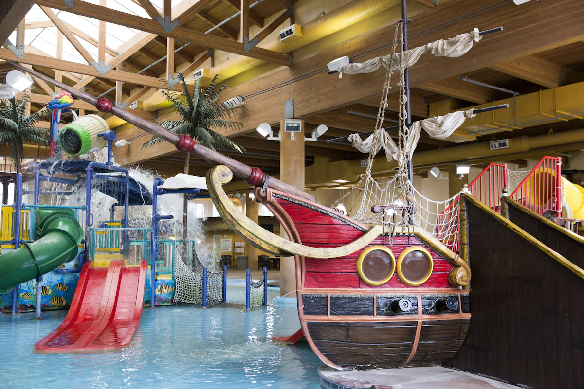 Indoor water park with red boat and blue water, resort in Iowa