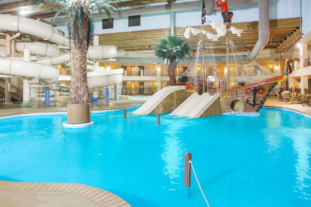 A pool with a pirate ship and slides in the centre. There is also a palm tress and a white water slide. 