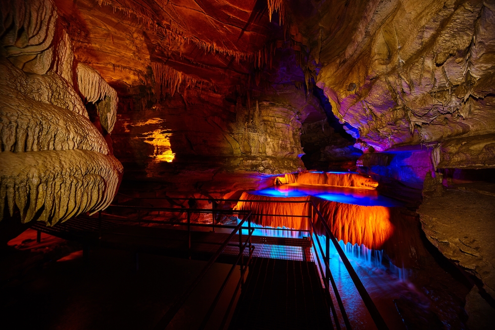 Steel walkway inside Squire Boone Caverns with lit pools of water and cave formations in one of the best caves in Indiana.