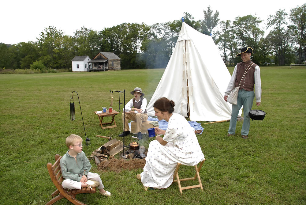 People dressed in pioneer clothing in a camping scene at the Historic Daniel Boone Home.