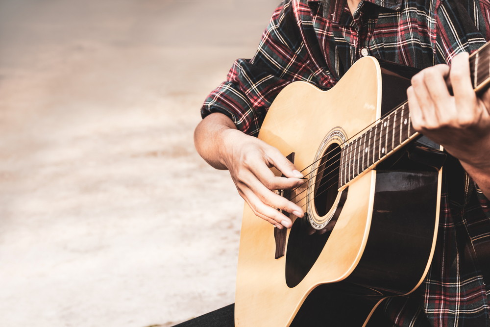 Close up a man's hands playing acoustic guitar. The article is about events in Wisconsin