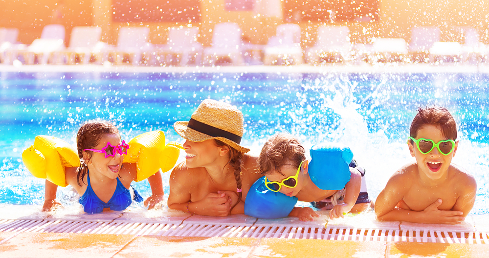 A woman and three children wearing sunglasses playing in the side of a pool on a sunny day attractions in ohio