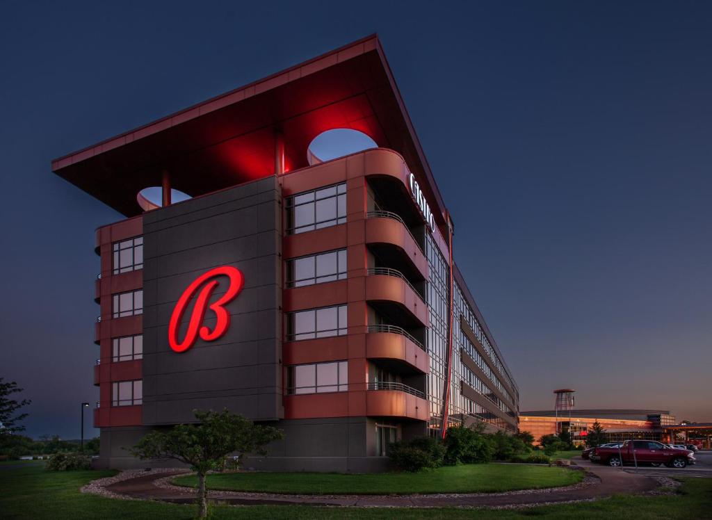 Large hotel building at night with a large B on the side. It has curned sides and is a brown and balck color. 